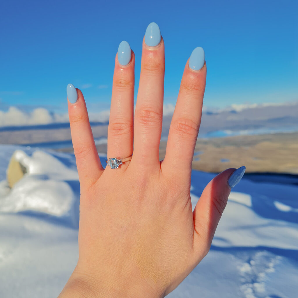 Custom topaz and diamond trilogy ring on hand after proposal