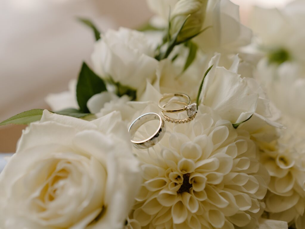 Kelly and Cam custom wedding and engagement rings on white bouquet