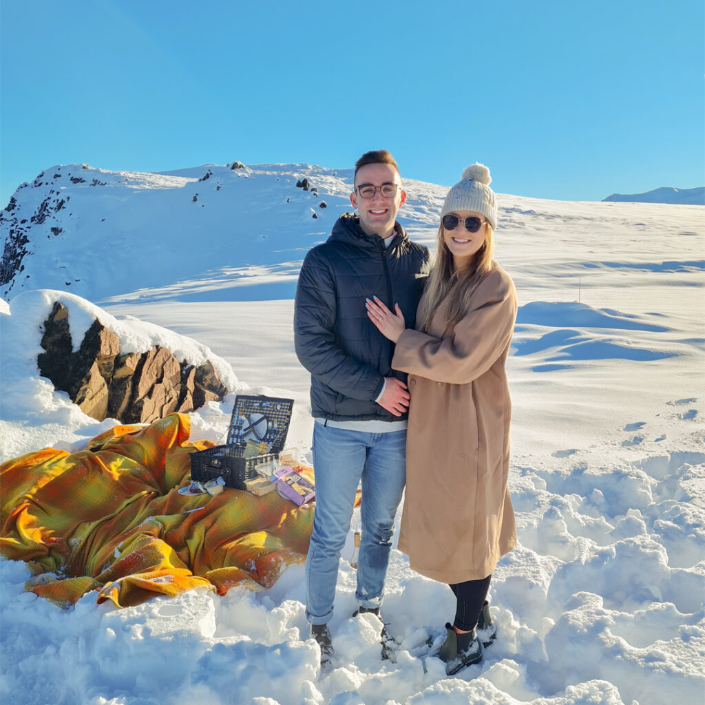 Nathan proposal ontop of a snowy mountaintop