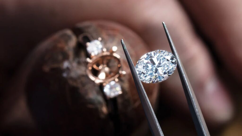 Jeweller setting oval diamond ring in workshop
